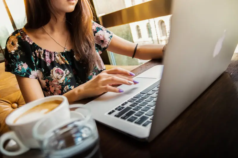 Person using a laptop with a cup of coffee and a glass of water on a table.