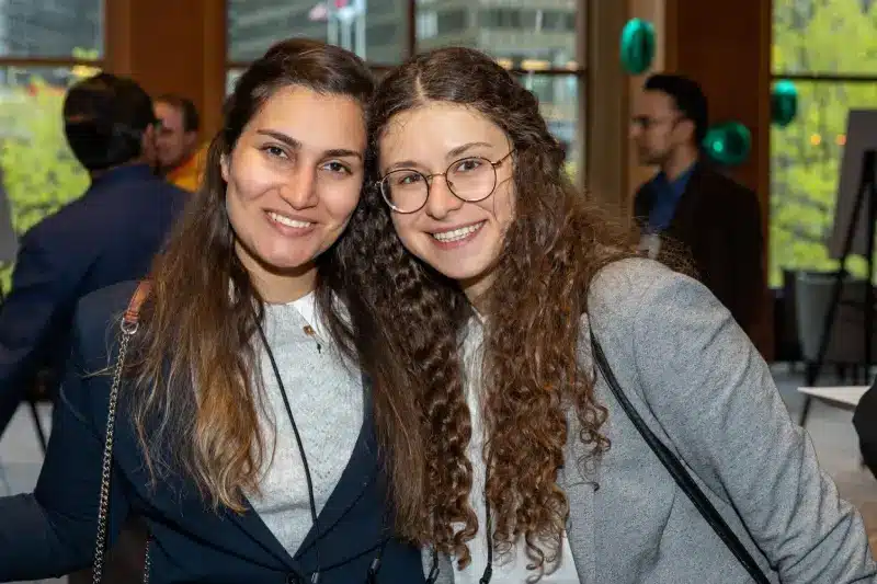 Two women smiling and posing together at an indoor event.